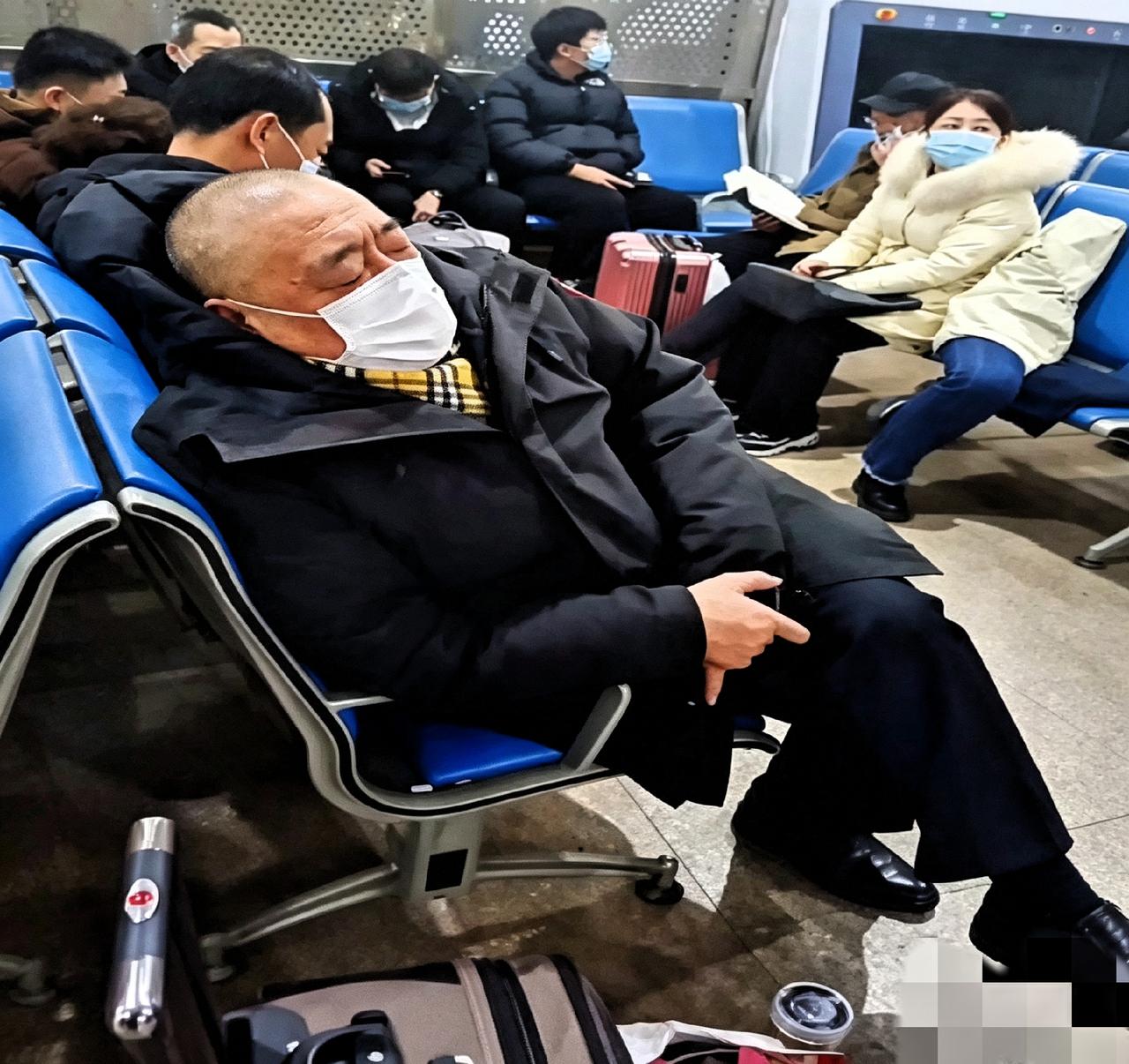 候车厅里，崔培军靠着椅子睡着了。旁边就一个行李箱和水杯，看着真挺累。对员工那么大