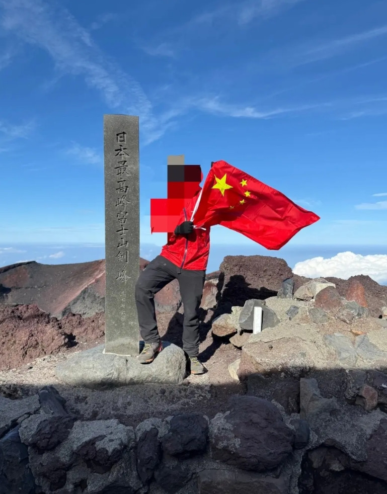 中国游客在日本最高峰富士山山顶展示中国国旗。攀登富士山，吸引了很多游客。登上海拔