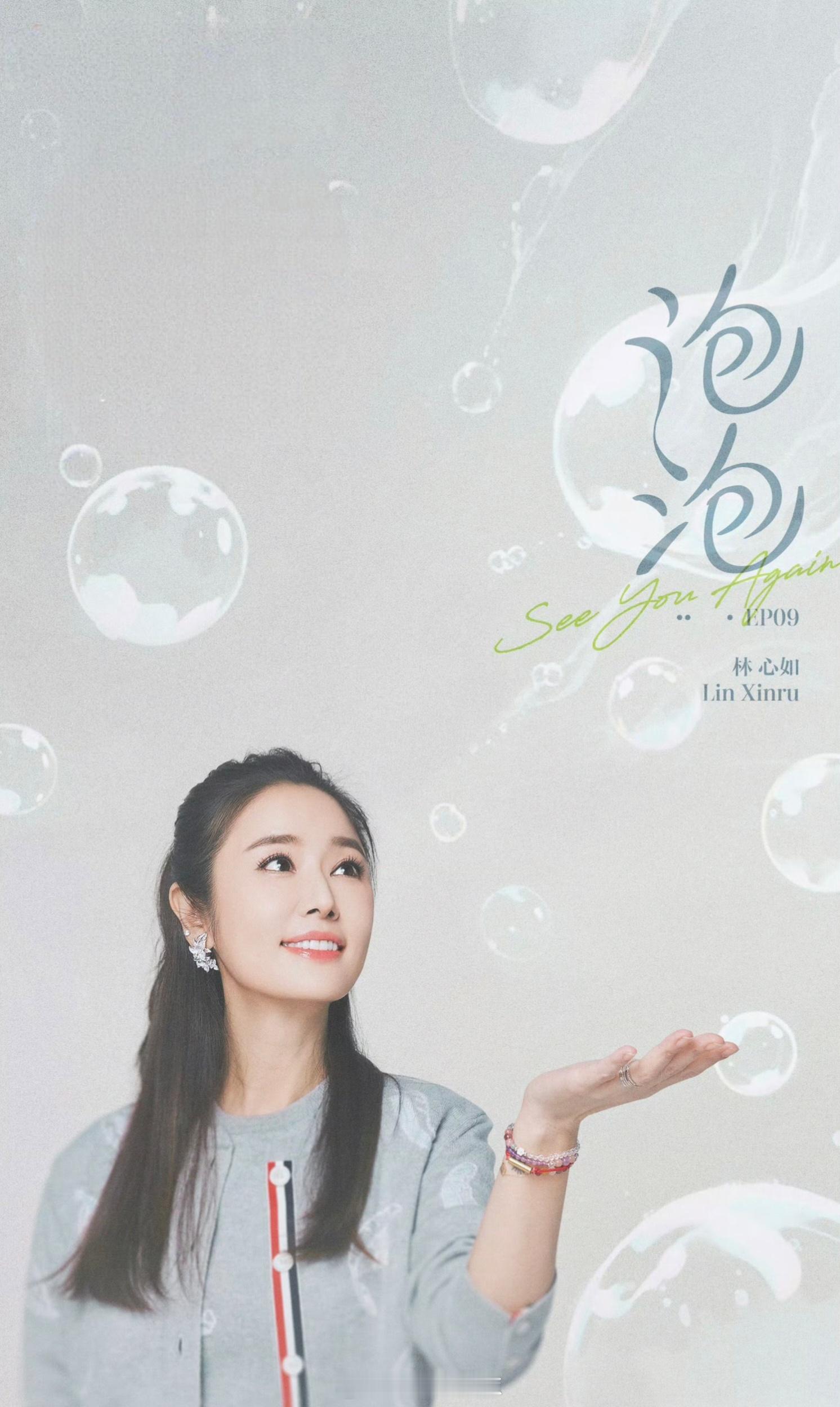 林心如浅灰开衫裹着松弛感，红白条纹纽扣藏着小俏皮，抬手轻接泡泡的瞬间，连笑容都