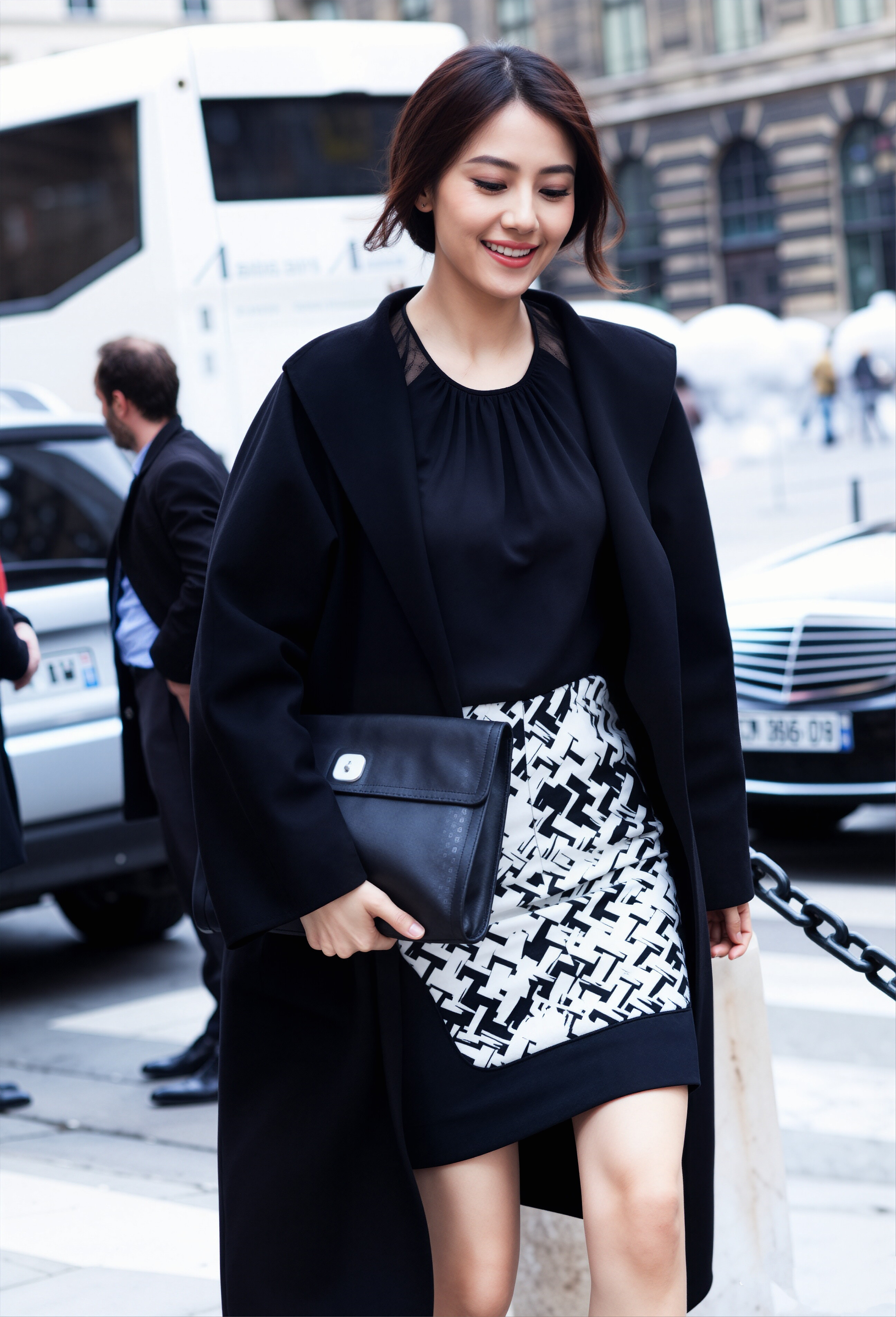 高圆圆街拍完美展现了可盐可甜的时尚表现力。第一张身着长款黑大衣搭配几何纹半裙，
