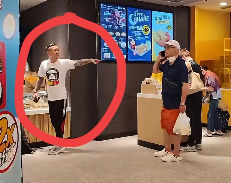 图中的纹身男和眼镜男因为麦当劳排队问题发生口角，纹身男自称香港三合会成员，来恐吓