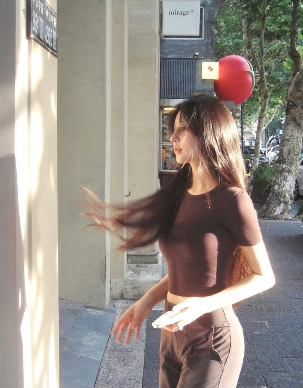 阳光为她的轮廓镀上柔金，飞扬的发丝在风中奏响自由的旋律。她双臂高举，舒展的姿态里