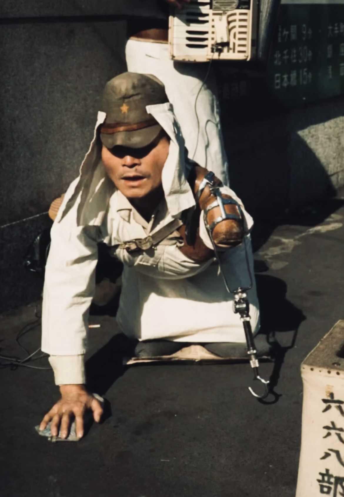 一张1966年的照片，照片中一位残疾的日本老兵跪在街头乞讨，他头戴军帽，身穿白色