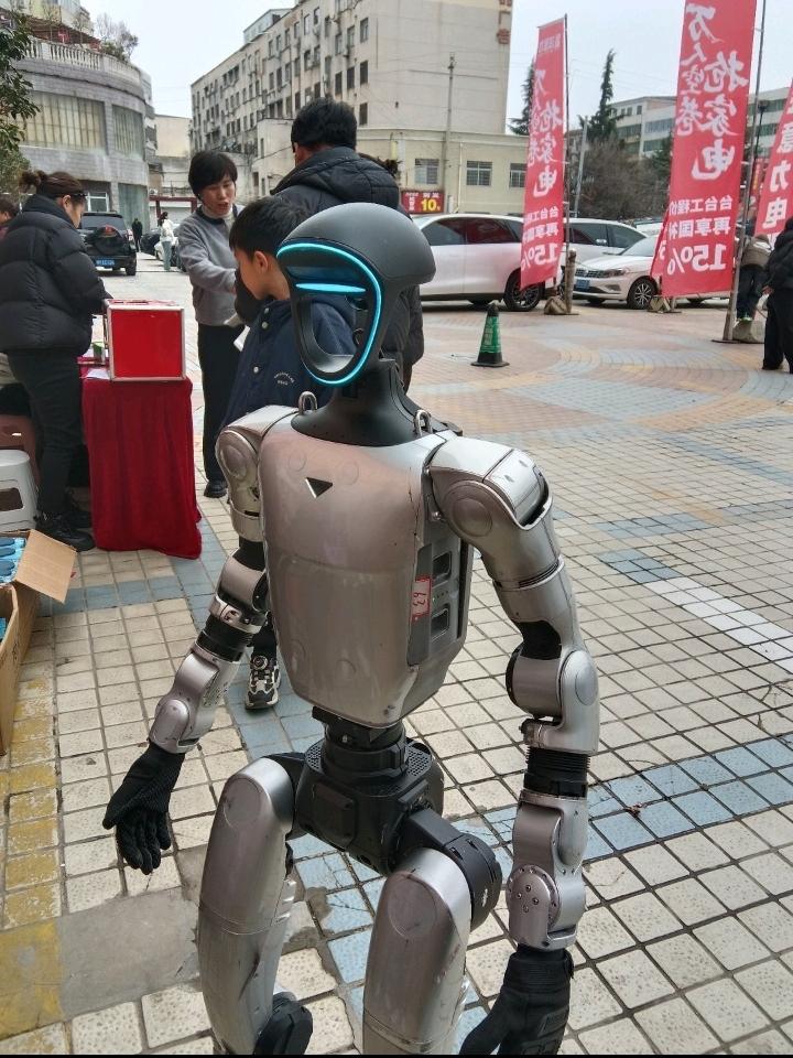 你看这街头突然冒出来的机器人，也太吸睛了吧！银灰色的金属机身，脑袋上还带着一