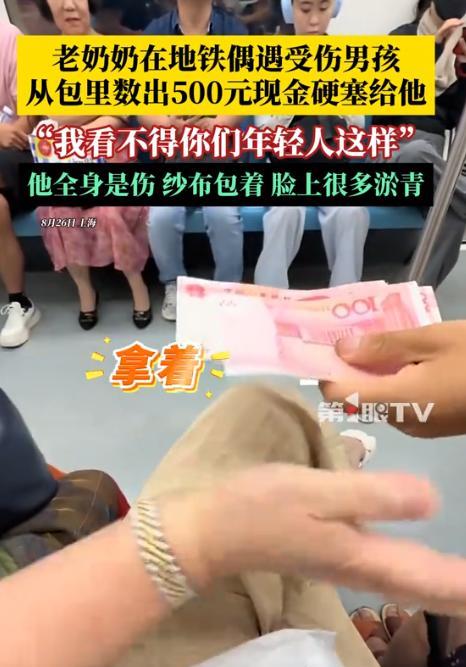 近日，上海，地铁上，一位男孩拿着500块现金，递给旁边的陌生奶奶，奶奶连忙摆手拒