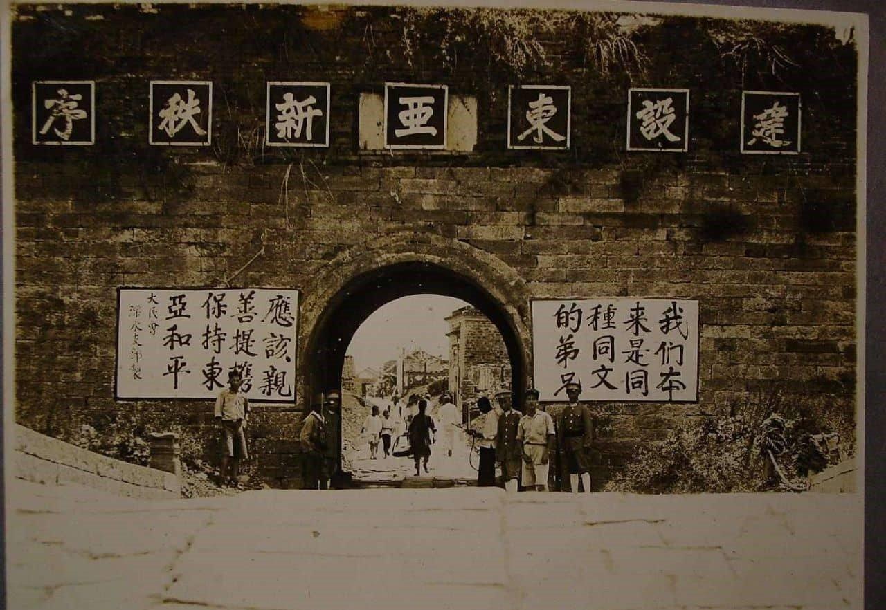 这张照片反映的是日本侵华期间在占领区的城门放置的宣传标语:建设东亚新秩序我们