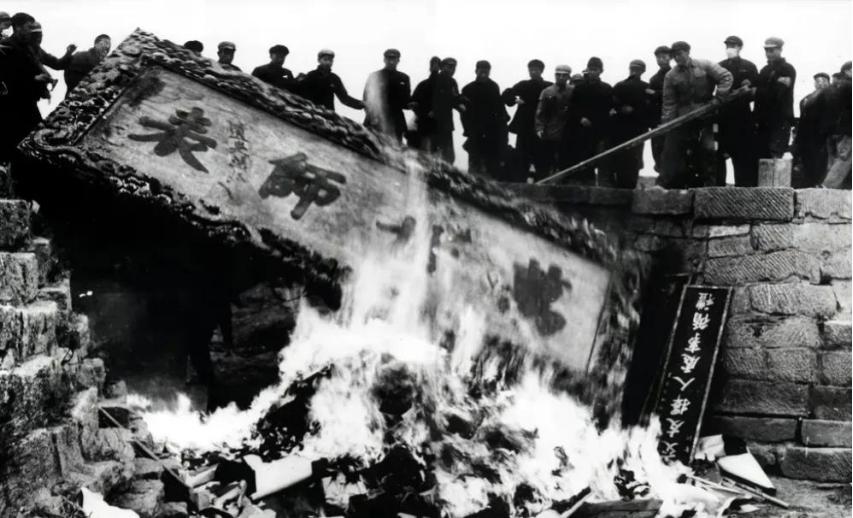 1966年，山东曲阜。年轻人用竹竿将“万世师表”的牌匾挑了下来，并放火烧掉。