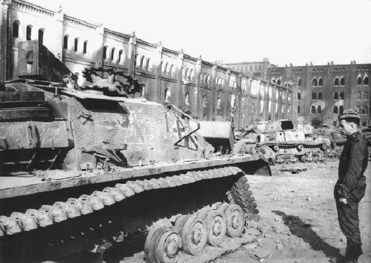 1945年一名苏联技术兵正在维也纳的军械库中检查一辆受损的德国StuGIV自行火炮。该车配备了带有宽