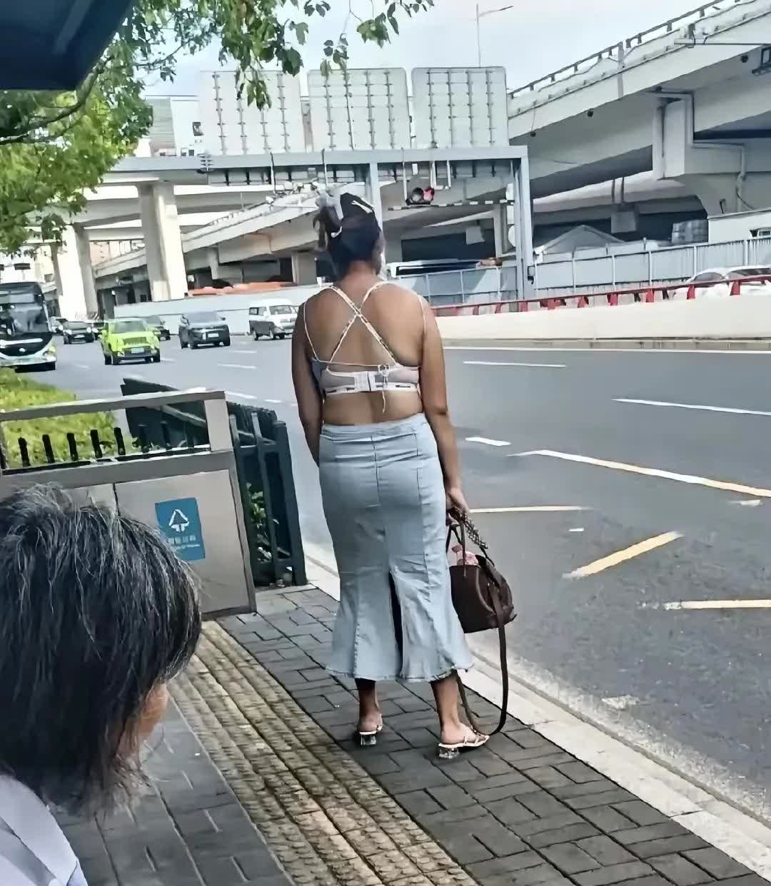 上午出去买菜时，无意间看到一个女子在等公交车。其他人都在站台阴凉处等车，她却独自