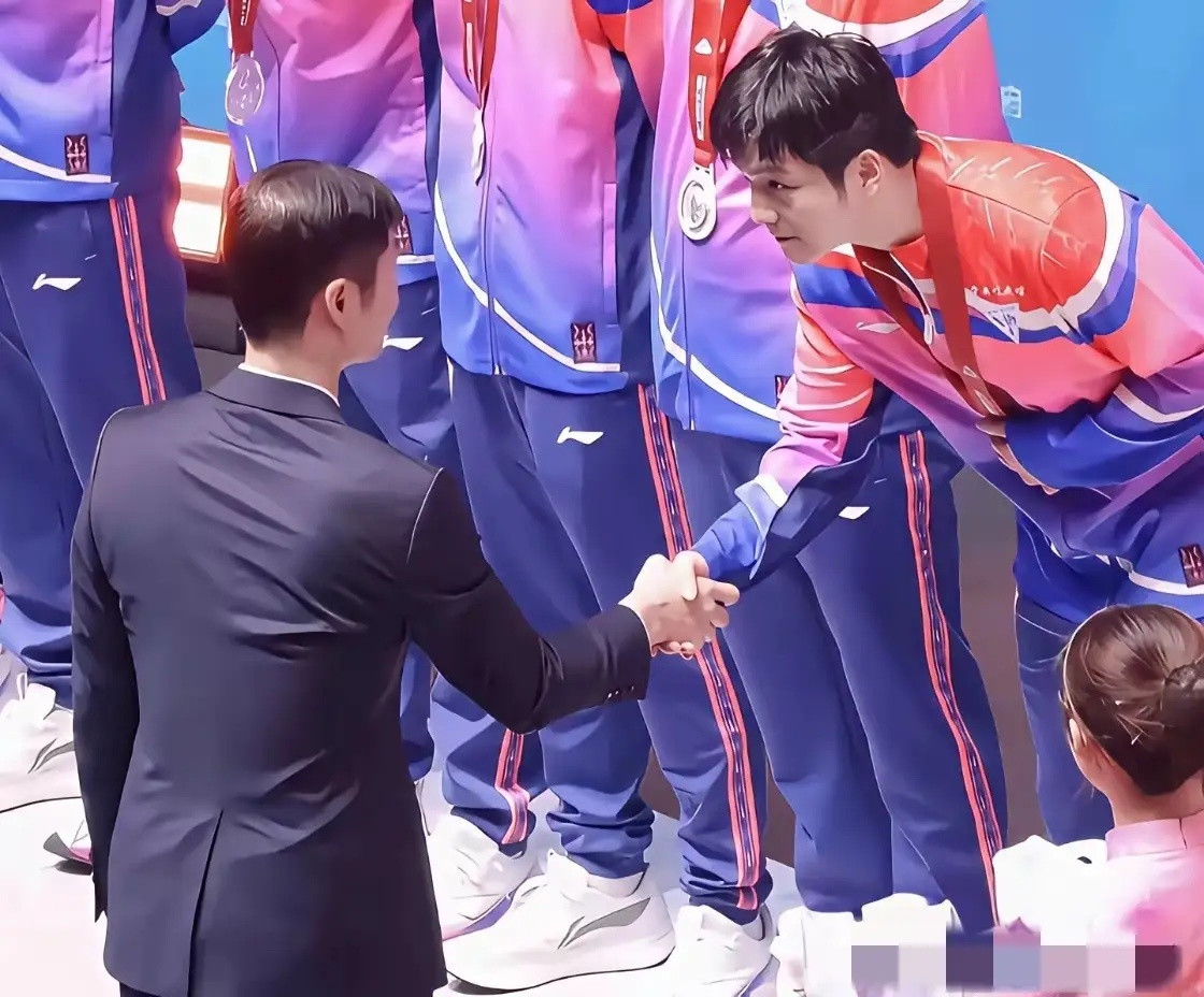 樊振东握手礼仪获盛赞！颁奖仪式上，王励勤惯例先握手再发吉祥物。到樊振东处，他目光