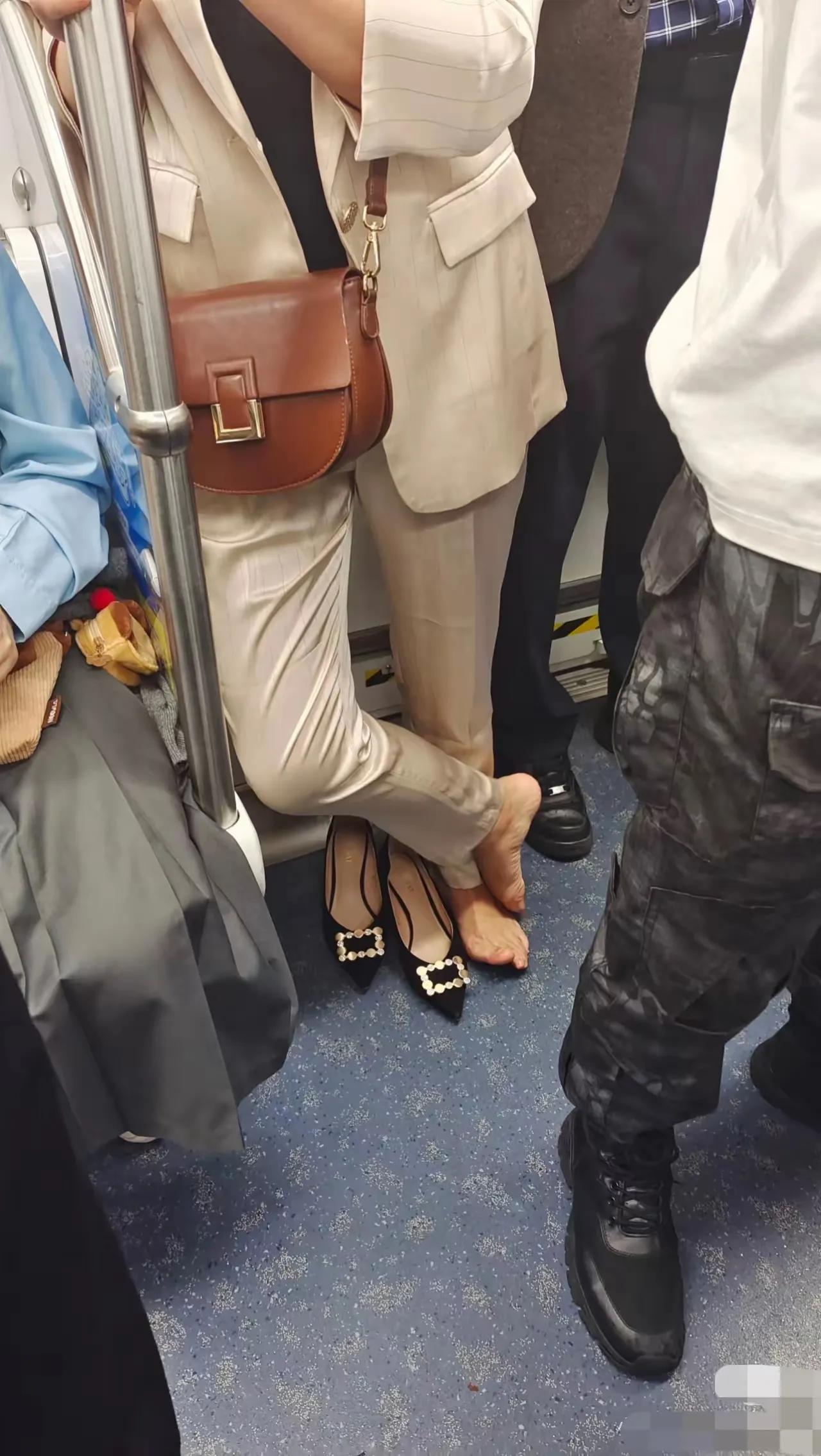 女人为了美丽穿着高跟鞋出门，看样子实在是难以忍受了，便在地铁上把鞋脱了。即便要站
