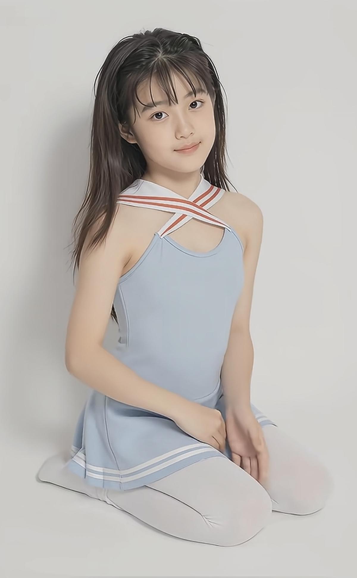 一个穿蓝裙的小女孩坐在地上。