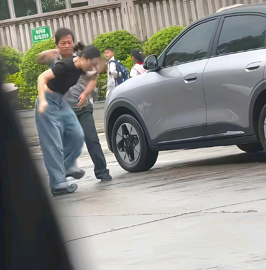 路人视角:疑似女车主和保安大哥发生争执，女车主对保安大哥抬腿一脚，保安大哥也不惯