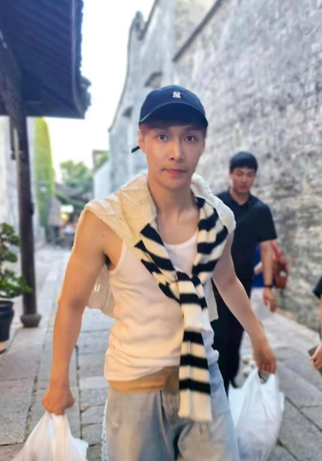 张艺兴在浙江乌镇逛街被偶遇，他穿着白色背心，看起来很瘦，皮肤非常白皙，很有少年感