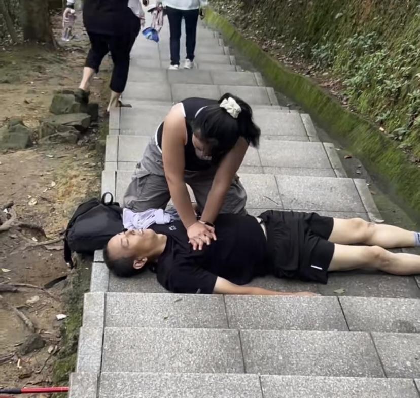 男子爬山突发身体不适晕倒在地，心脏骤停，脸色惨白，嘴唇发黑，好心女子上前施救。6