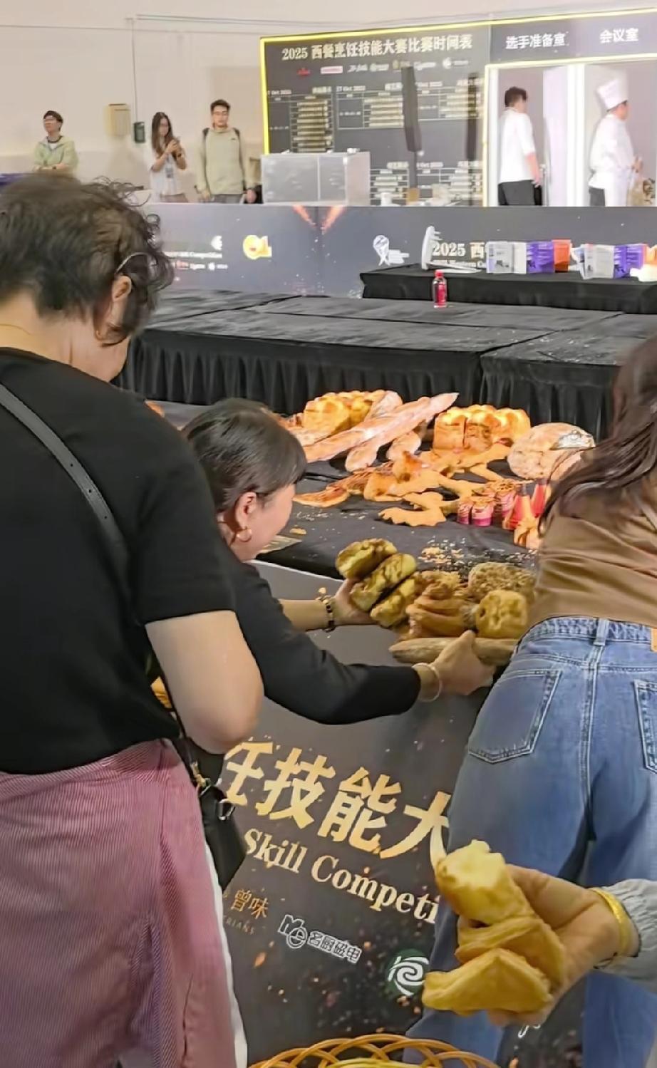 苏州。中国厨师节展区现场，大妈们推倒护栏拿走用作比赛作品的面包，远处的厨师小哥真