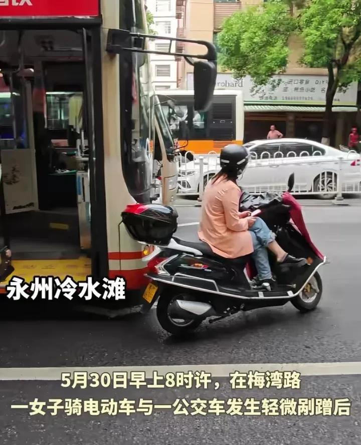服了！女子剐蹭公交车，淡定坐在电动车上玩手机！半条街瘫痪！5月30日上午8时许