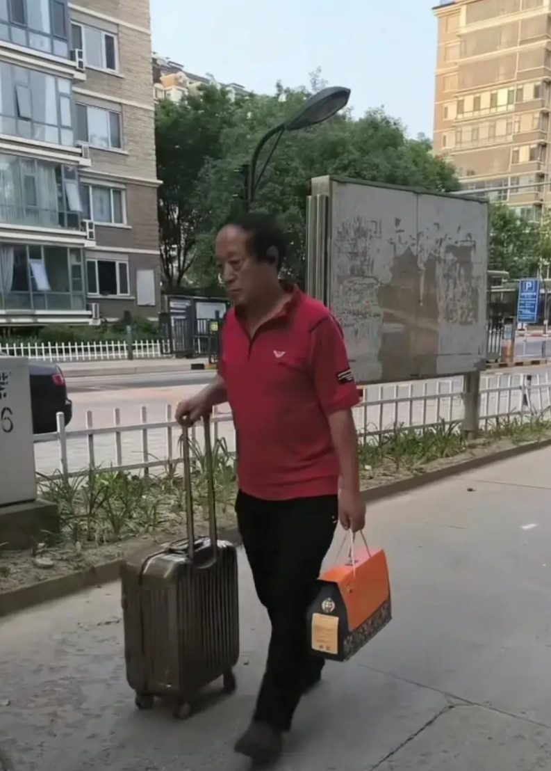 这是相声演员牛群最近从山西参加活动回北京住宅的情景。他穿着朴素，一脸沉重，右手推