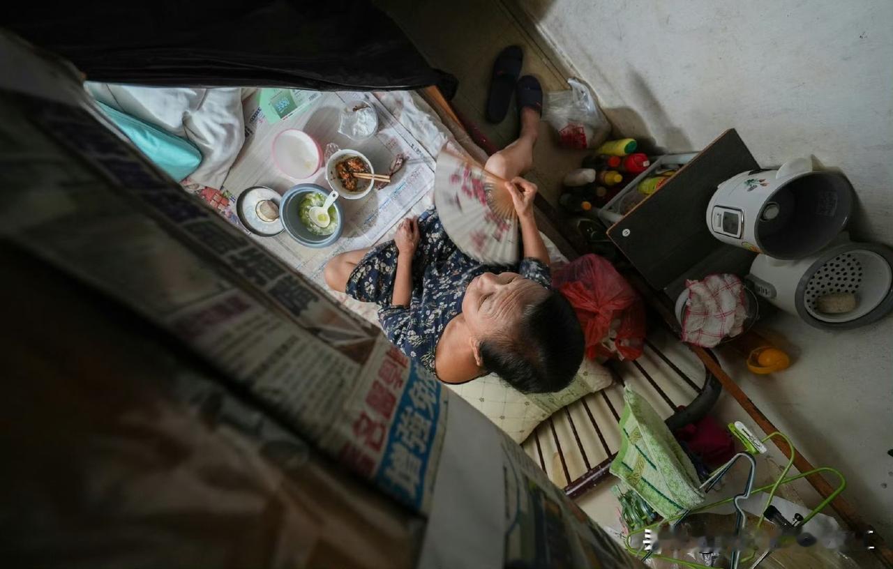 香港劏房：64岁的戴女士住在“棺材隔间”里，在她那四英尺宽的床铺上吃晚饭，她四年