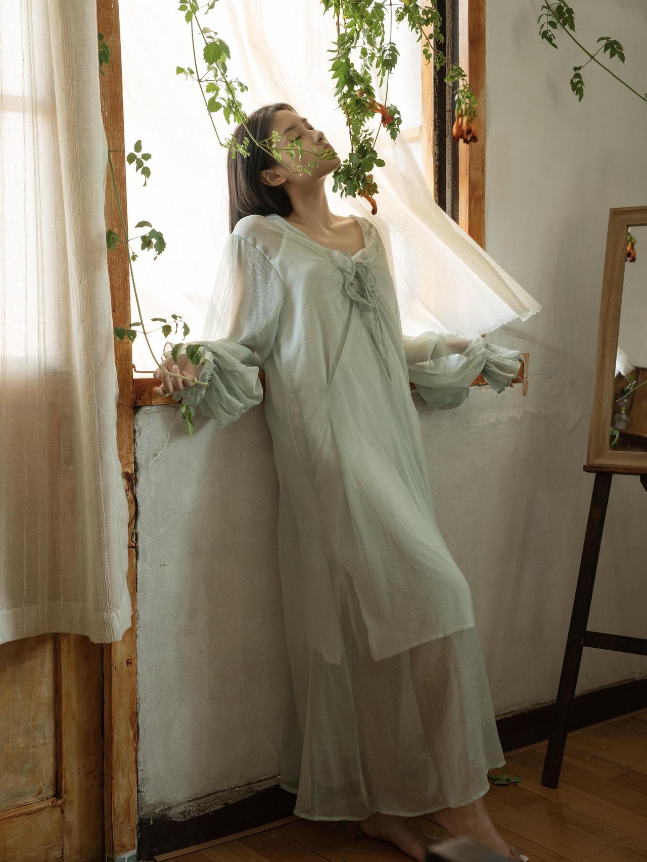 在这张以纱帘和绿植为背景的照片里，少女的静谧思绪被很好地捕捉到了。飘动的纱帘、摇