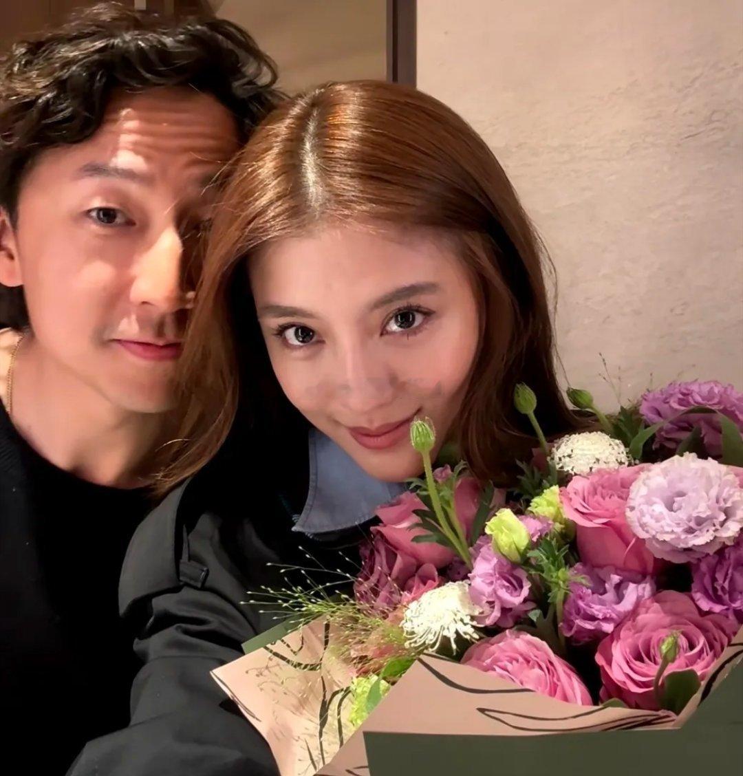 吴千语晒节日照，怀里抱着鲜花和老公合影，两人用情侣手机壳好甜，施伯雄看着她笑得一