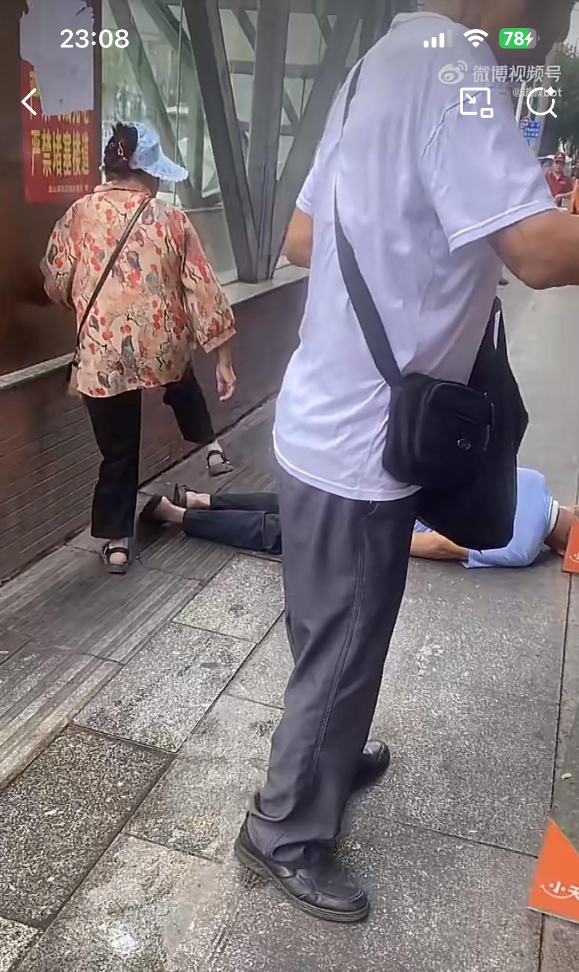 重庆某地街头，一个老人扑倒在地，不知道是生病了还是其他的原因。它刚好横在狭窄的人