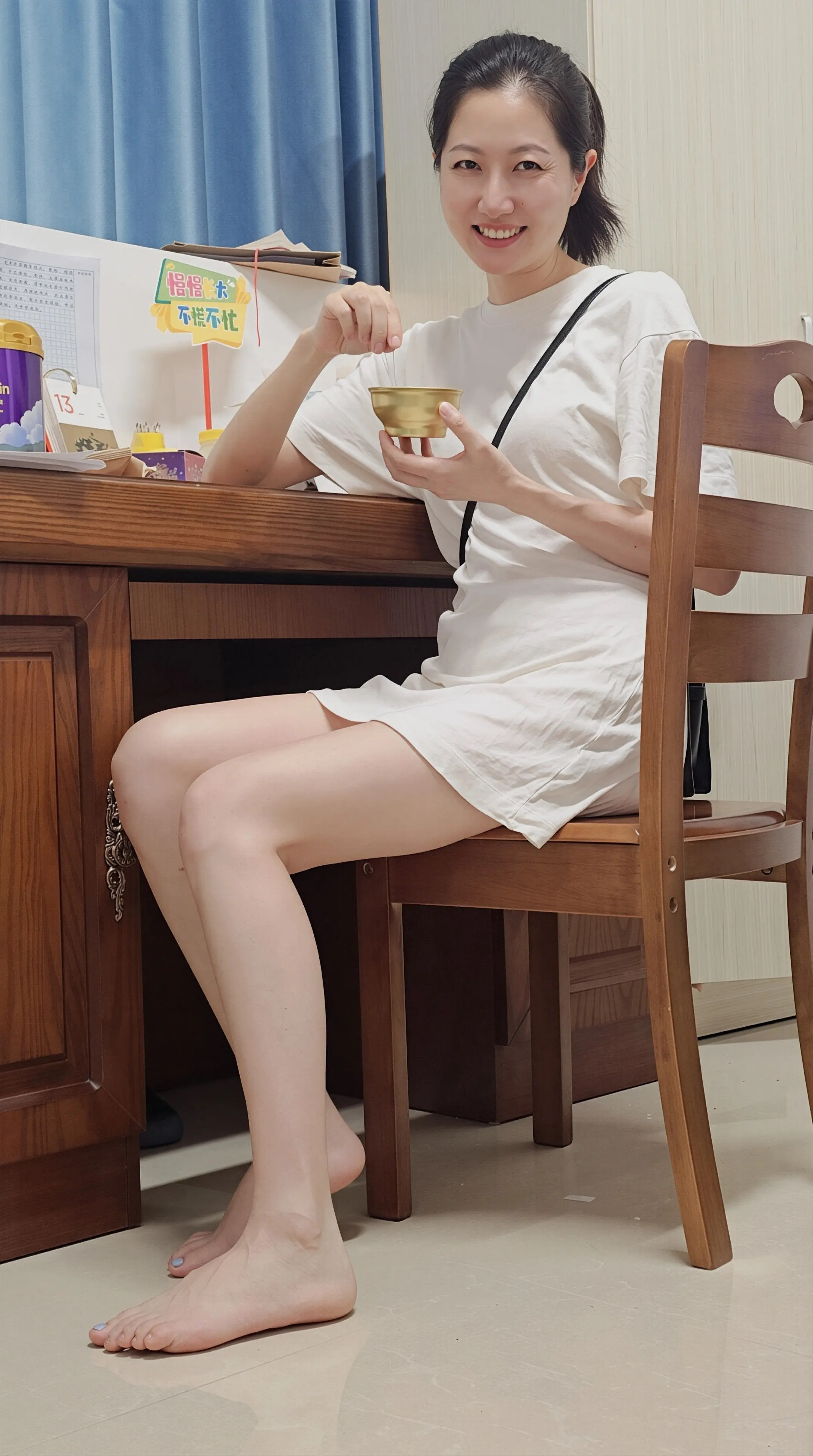白T恤裙简约舒适，赤脚居家尽显松弛感。笑容灿烂治愈，手持金碗添趣味，慵懒随性风太