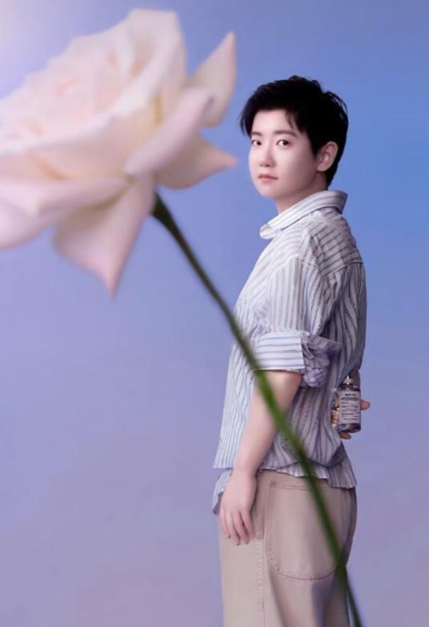 那朵花，我发誓在别处见过。绸缎材质，渐变粉紫，以同样的角度别在条纹衬衫的第二颗