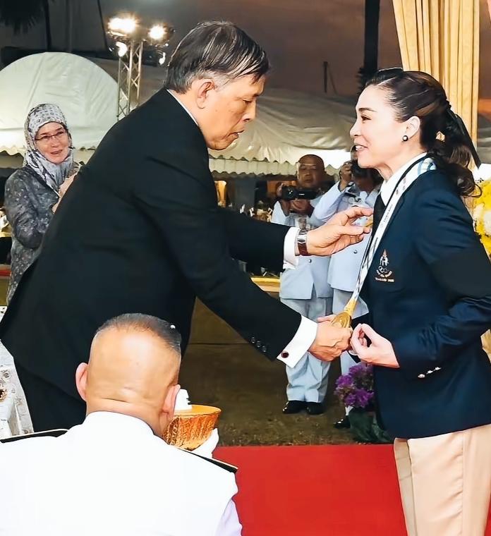 苏提达面对国王亲自给戴上奖牌，是不是有些紧张了啊？苏提达这面部表情很特别啊！