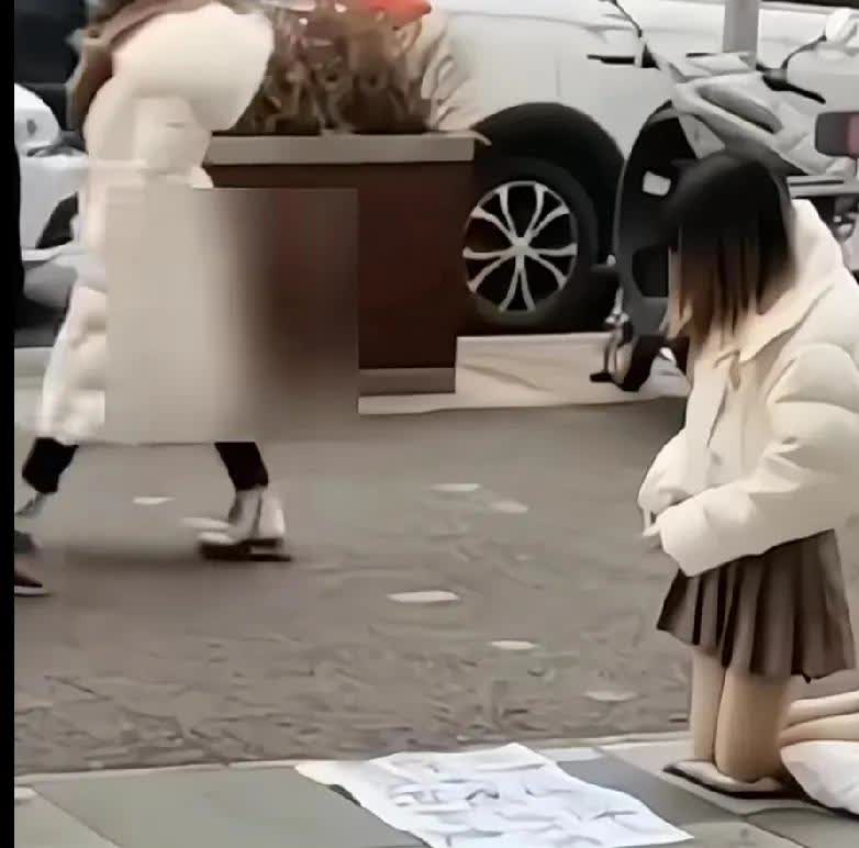良心过得去吗？年轻美女穿着干净，讲究，白色羽绒服加短裙保暖袜跪在街头，面前白