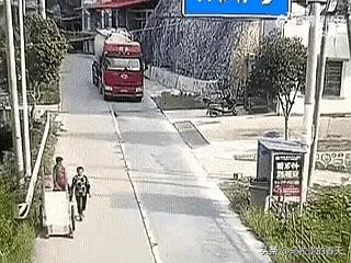 大妈先是在轿车跟前晃悠两下，看司机没打算惯她这毛病，扭头就往大货车轮子底下钻。