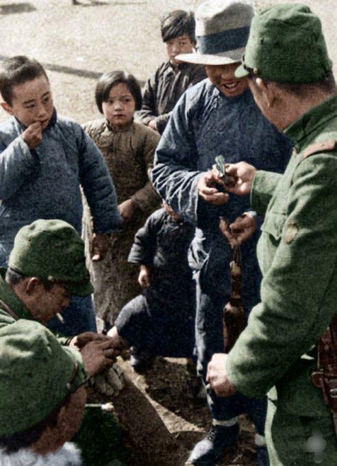 南京被日军占领14天后，一名日本兵蹲下身，右手拿着几张纸币，正递给一个中国小女孩