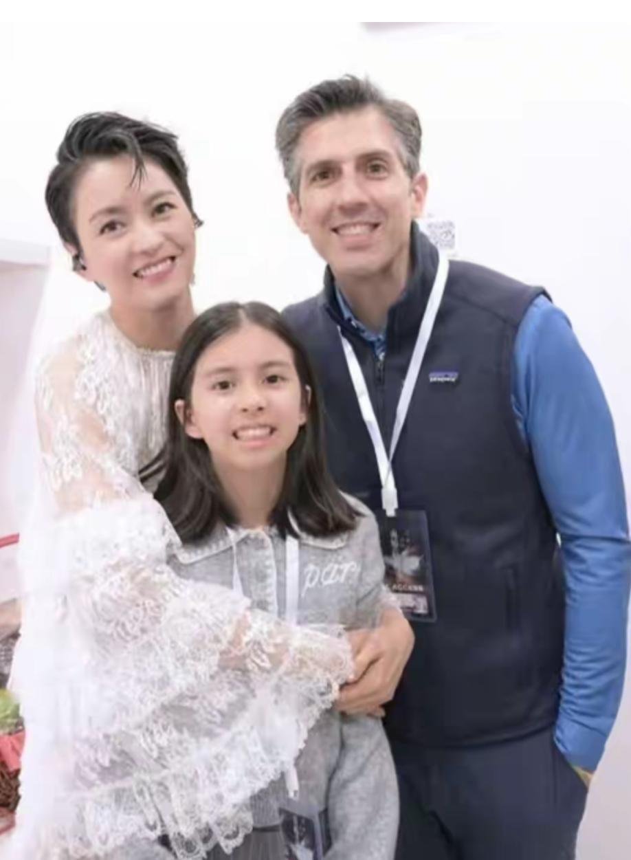 让我们一起来欣赏一下梁咏琪的全家福吧：镜头中的梁咏琪身着白色蕾丝长袖上衣，短