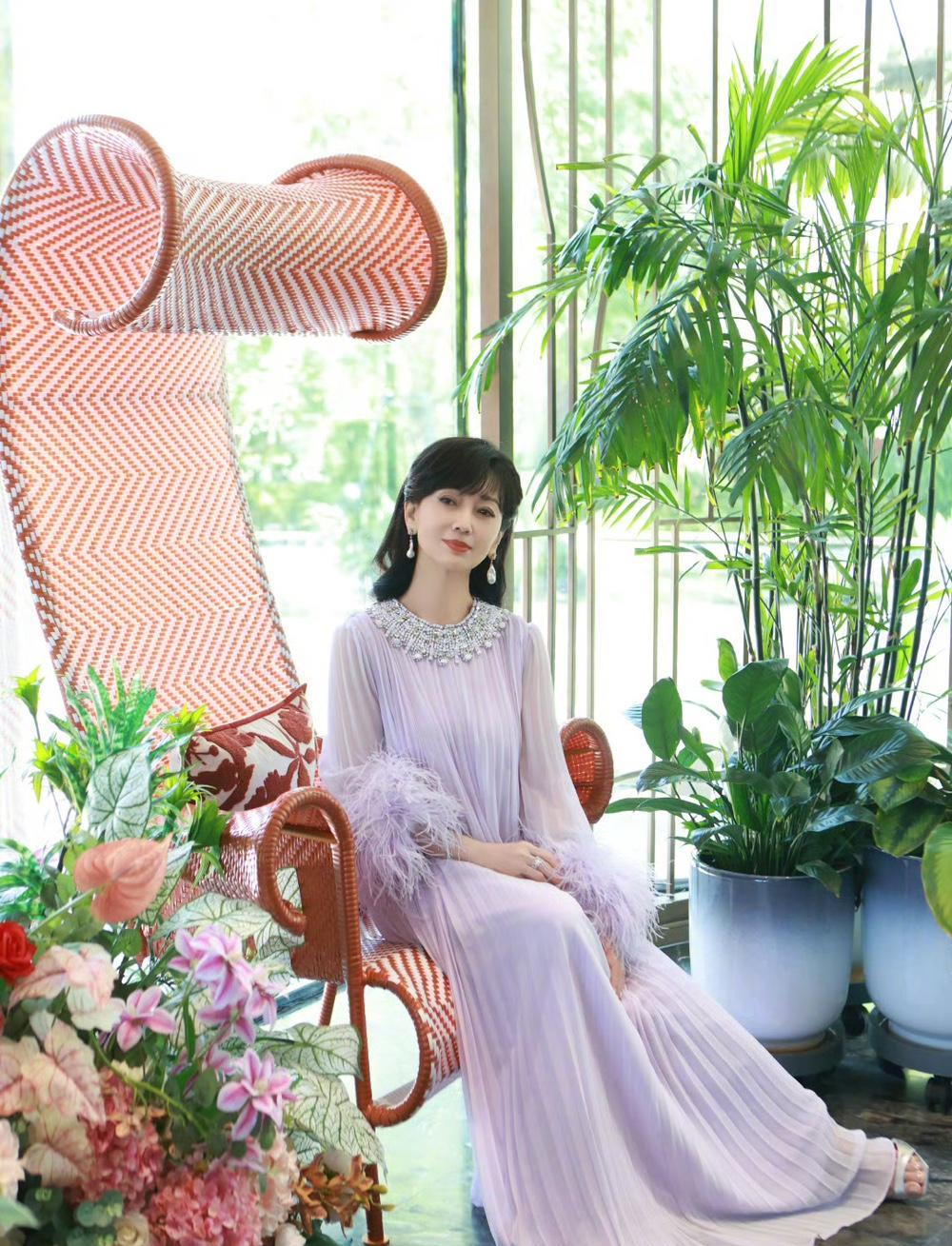 赵雅芝一袭浅紫色长裙落座其间，裙摆如花瓣般轻盈舒展，与满桌精致茶点相映成趣。她执