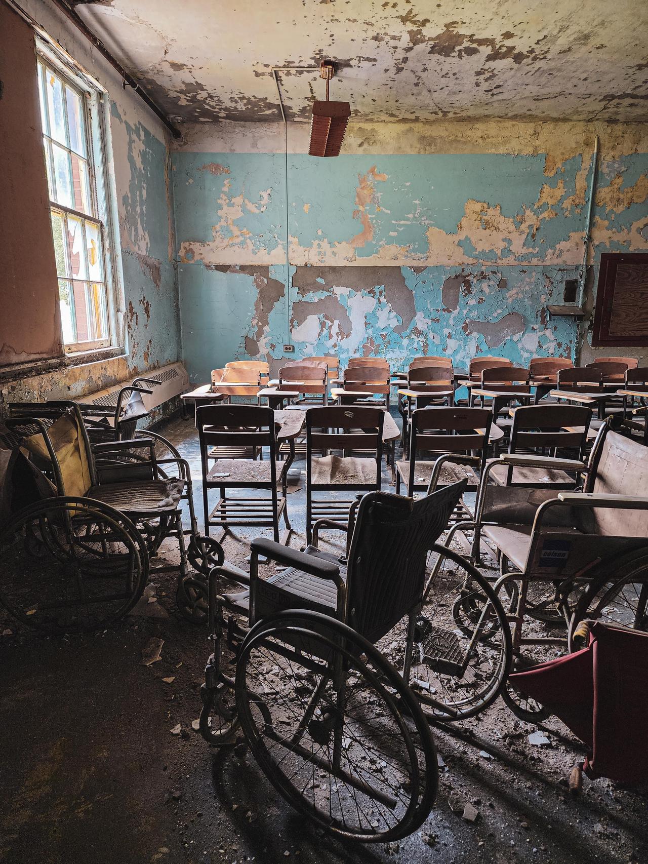 金斯公园一间废弃精神病院的教室，墙壁油漆剥落，桌椅散乱。照片可能拍摄于此，因有网