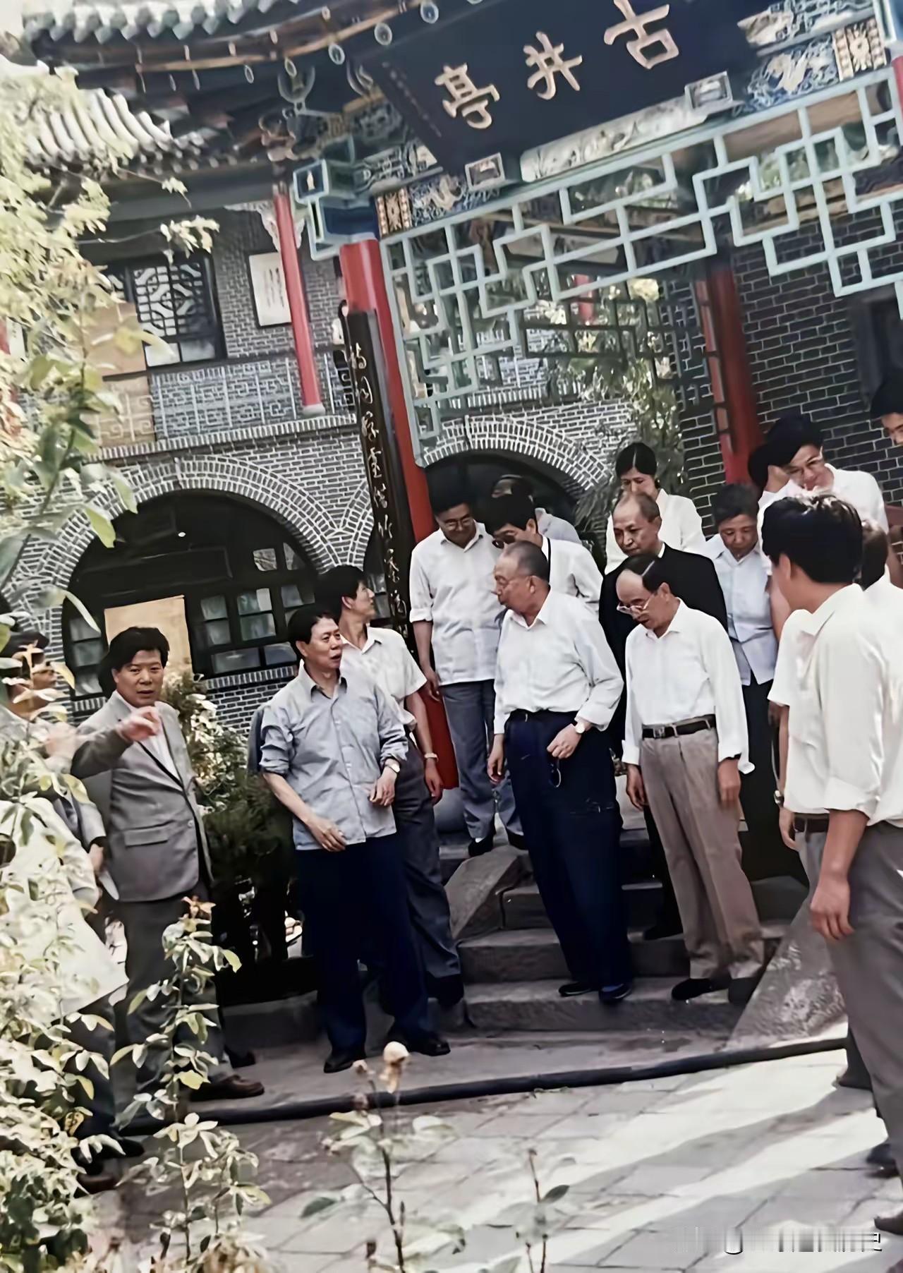 华老一行莅临山东聊城视察，驻足于“古井亭”前。亭台古色古香，灰砖黛瓦映着盎然绿