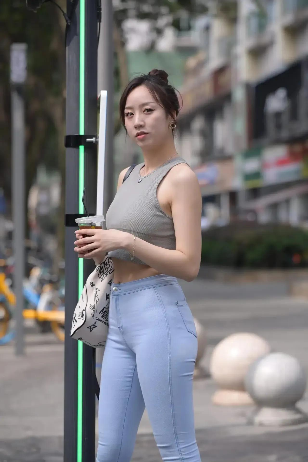 一个女孩在街头喝饮料。梨形身材怎么穿显瘦又显高?什么样的身材更适合穿无痕裤?