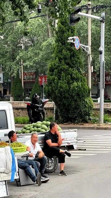 河南街头，三个卖瓜大叔正蹲在马路牙子上聊天，嘴里的烟刚点着。突然，其中一个黑衣