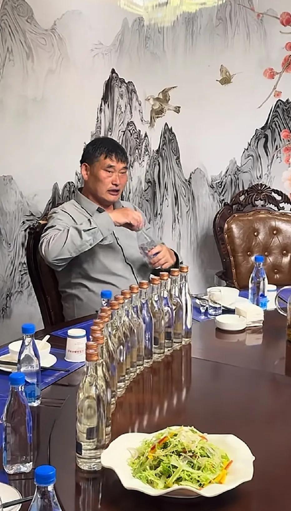 大衣哥演出结束后，受邀与友人们聚餐时的一幕，面前放满了光瓶白酒。大衣哥朱之文草