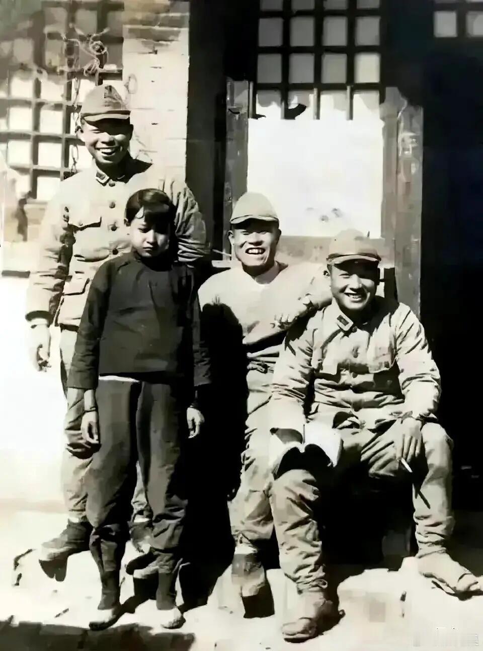 抗战时期，华北沦陷区的一户农家门前，三名日本兵与一名中国小女孩合影。鬼子手中夹着