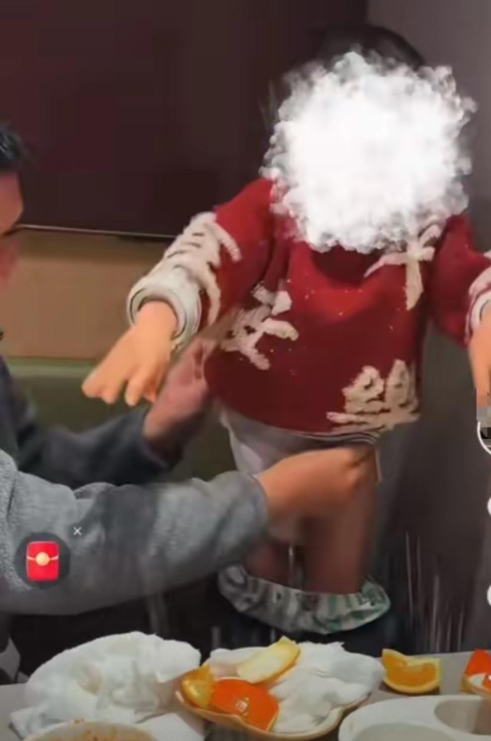 山东徐州，海底捞火锅桌旁，一年轻父亲，在给2岁幼儿换纸尿裤，年轻母亲则在对面拍