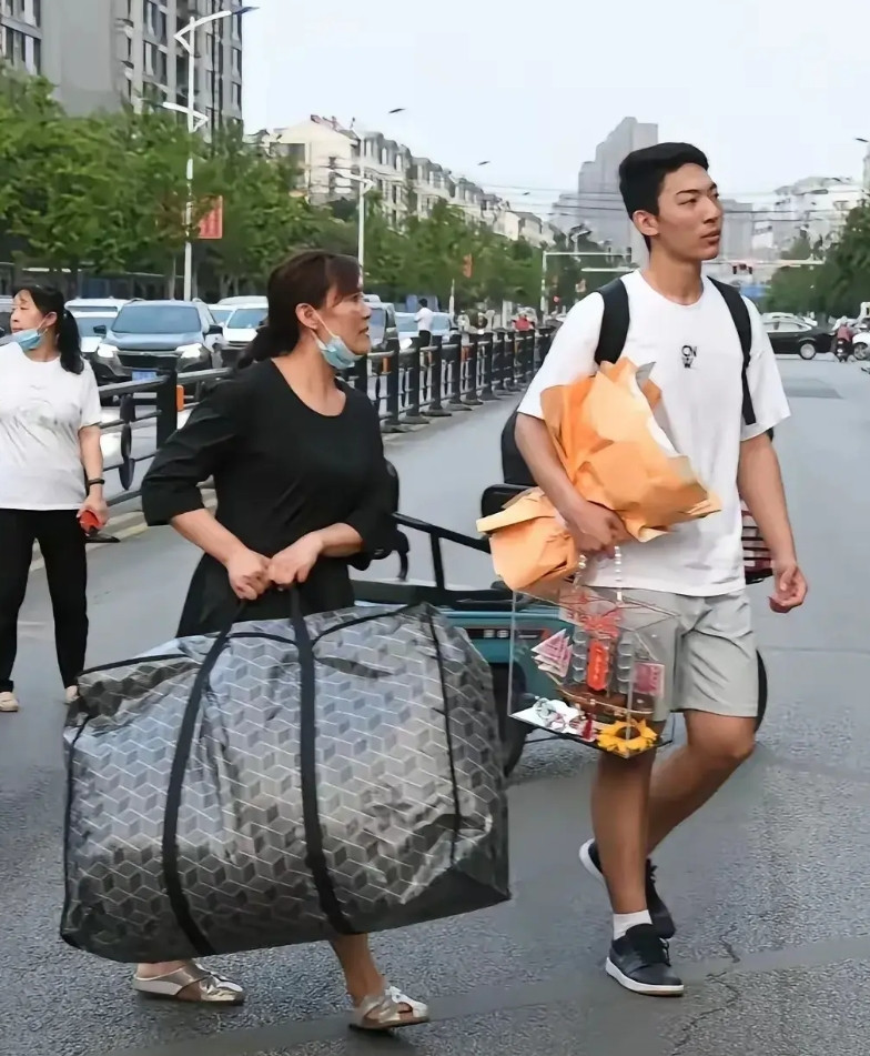 牛高马大的大竟然把最重的包裹留给了母亲，这和桂林挑扁担女孩成了鲜明对比。有人说