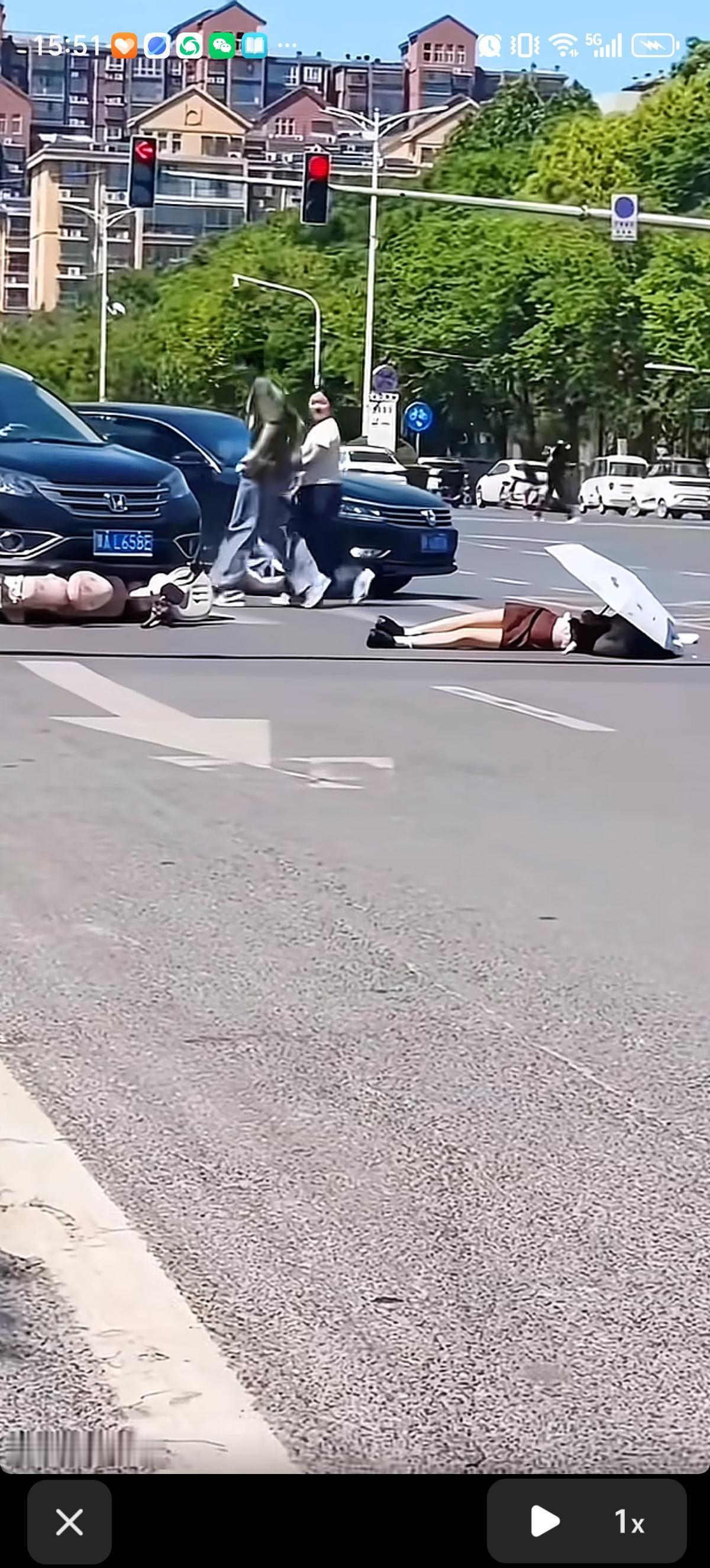 女子静静的躺在马路牙子上，头上盖着遮阳伞。电动车倒在离女子一两米远的位置，电动车
