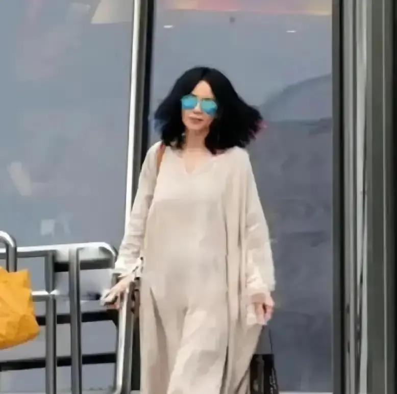 王菲穿件灰袍子踩双人字拖晃进机场，金边小圆墨镜一戴，照片一出全网疯转。不到一天
