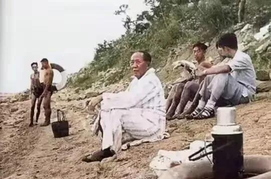 毛主席游完泳后，静静地坐在土地上，身上的浴衣还带着水渍。他就像一位邻家的老大爷，