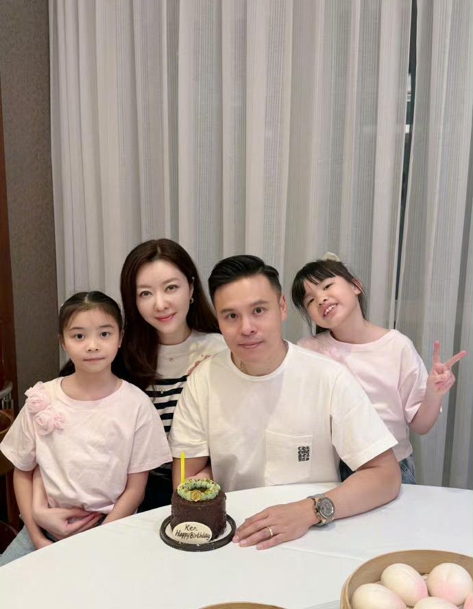 熊黛林和双胞胎女儿为她老公庆生。她的两个女儿，一个坐在她腿上，一个站着比着V型手