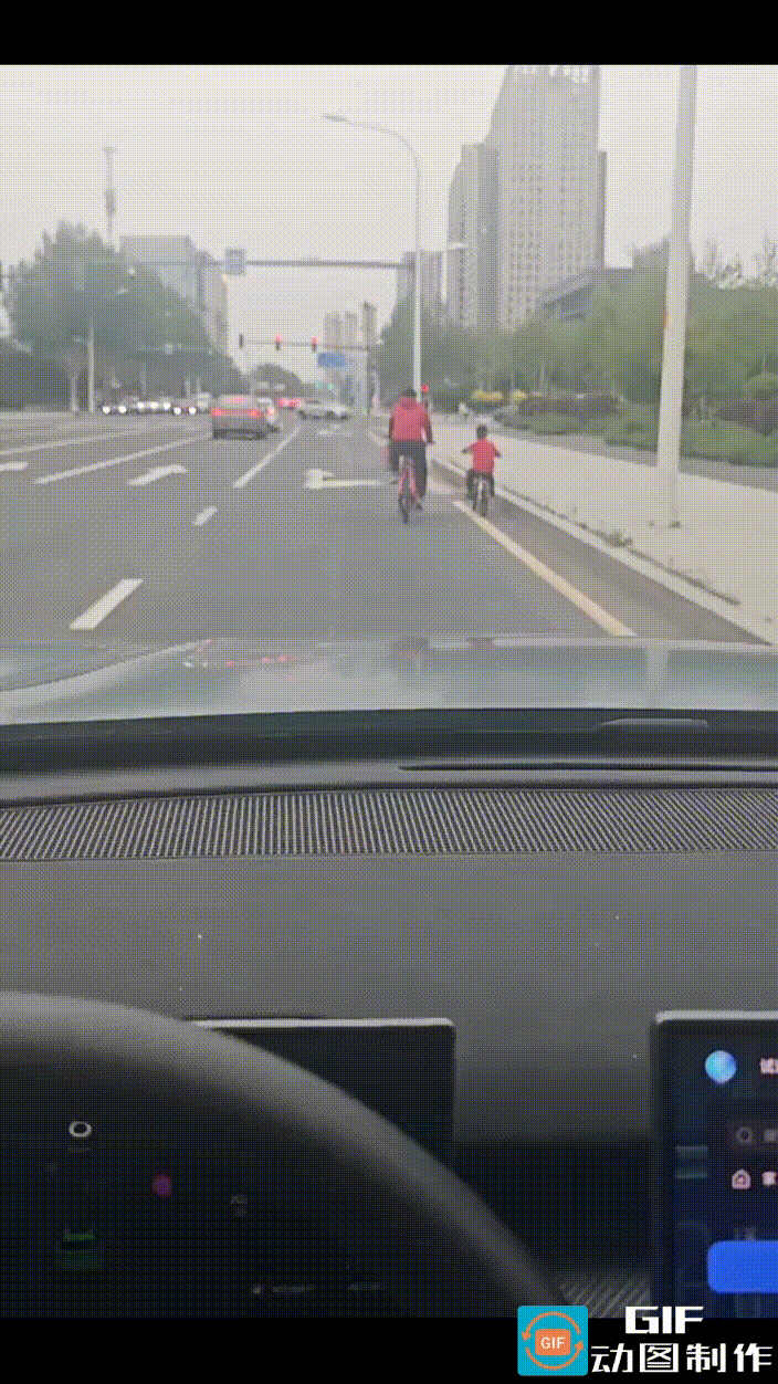 行车记录仪清晰地记录下了这一幕，父子俩骑着自行车，慢悠悠地走在机动车道上，完全不