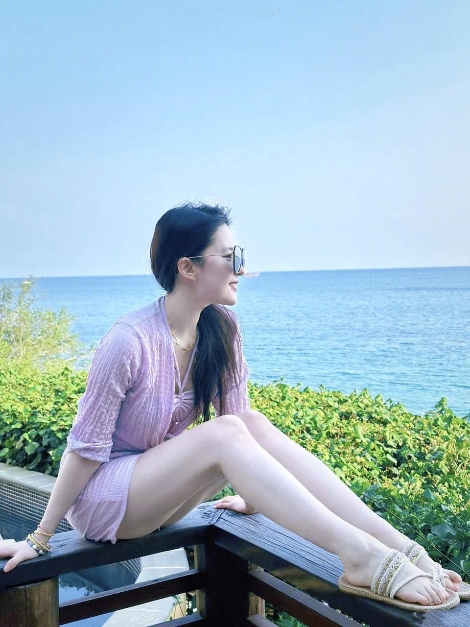 刘亦菲白裙漫过沙粒的褶皱蓝花别在发梢像把一整面海的呼吸别进了风里浪