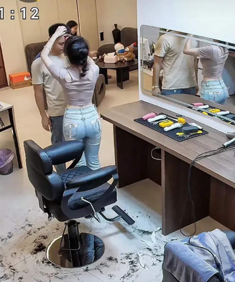 一位身材妖娆的女理发师面对面站着给男顾客清理面部，两个人的脸都快贴到一起了。看