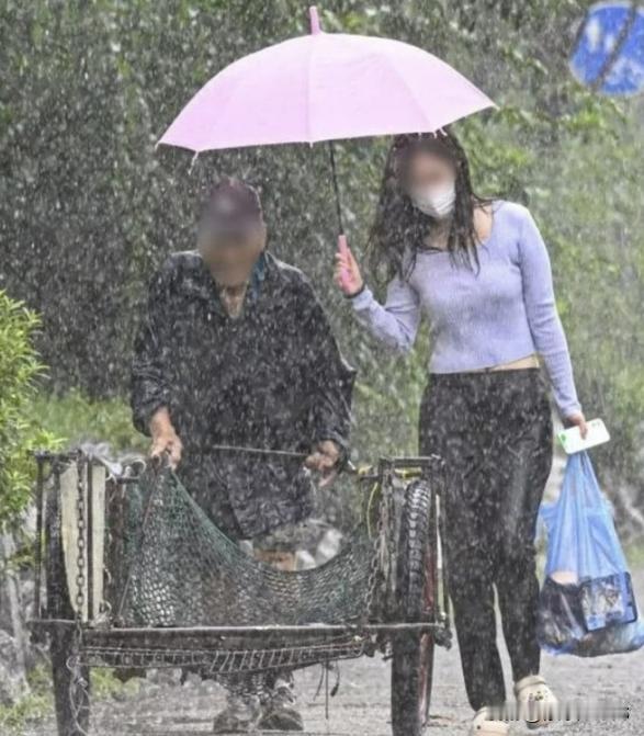 女人在雨中为拾荒老人撑伞，自己肩膀全湿透了，后续消息传开了在一个暴雨倾盆的日
